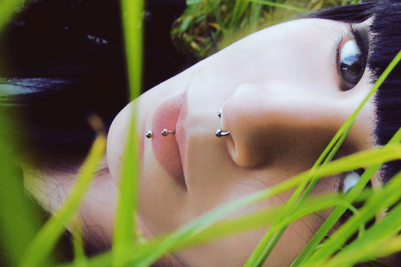 woman lying in the grass with a labret piercing septum piercing