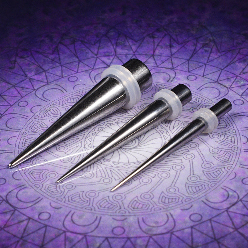 a selection of steel ear stretching tapers on a purple geometric background