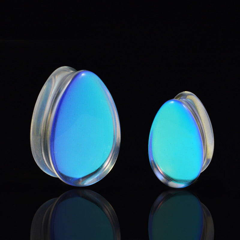 luminescent blue glass flesh plugs in a teardrop shape on a black background