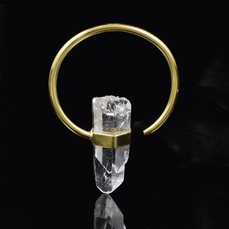 an ear hanger brass hoop with a quartz crystal on a black background