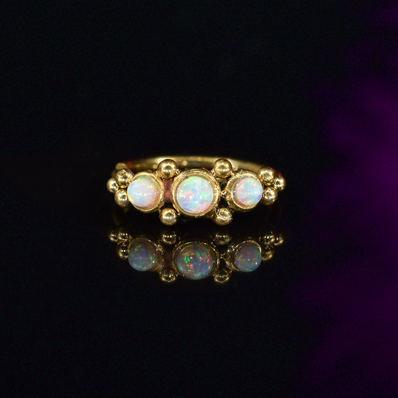 gold steel tribal nose ring with opal stones on black background