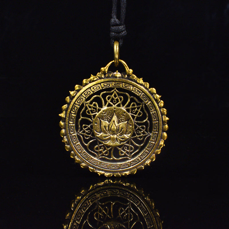 a gold brass pendant with a lotus and mandala design on a black background