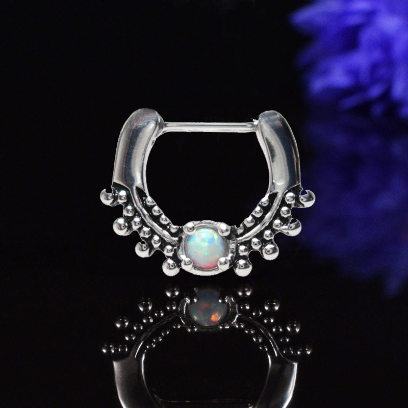 tribal style septum ring with opal stone on a black background