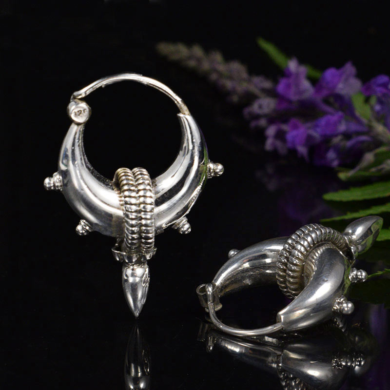 Silver earrings in a tribal design on a black backgound