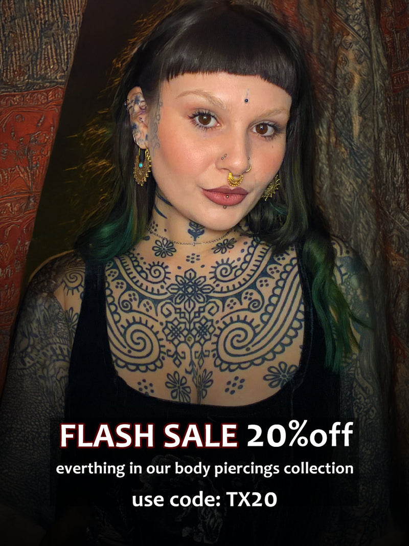 alternative woman with tattoos, tribal earrings and piercings standing in front of Indian drapes with sale text