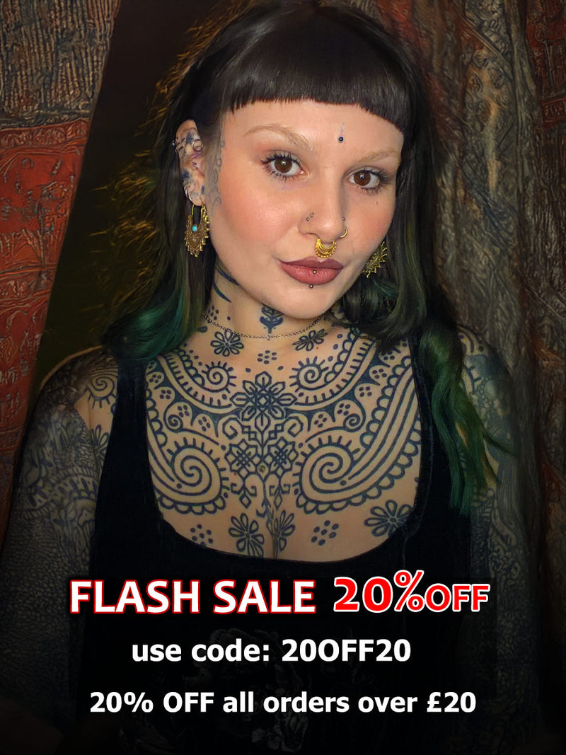 alternative woman with tattoos and piercings wearing a septum ring, nose studs and tribal earrings standing in front of indian drapes with a flash sale promotion
