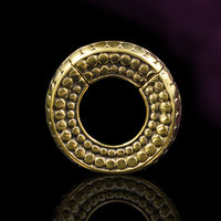 hinged clicker hoop ear weights with tribal dot design in gold brass on a black reflective surface