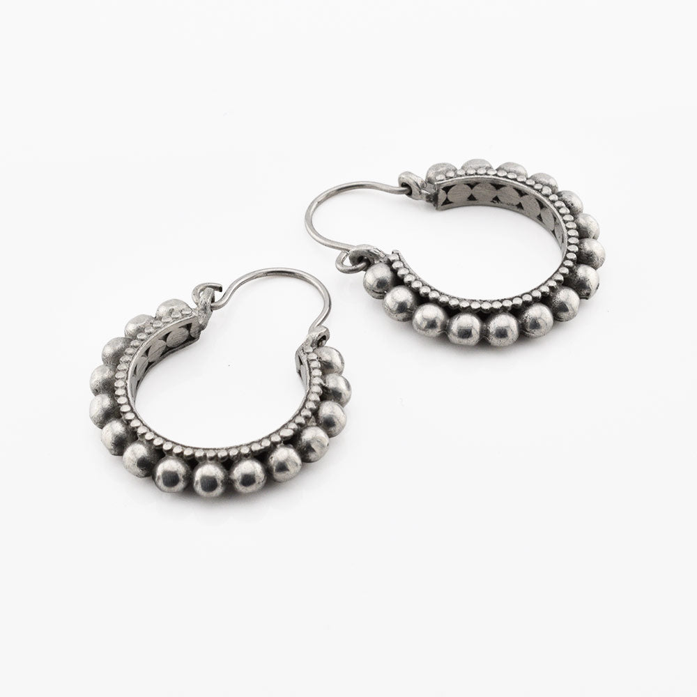 Pair of tribal silver brass hoop earrings with bead detailing on a white background