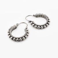Pair of tribal silver brass hoop earrings with bead detailing on a white background
