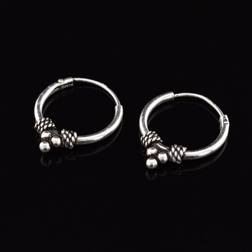 Silver bali earrings with triple dots and weave design on a black background