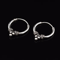 Silver bali earrings with triple dots and weave design on a black background