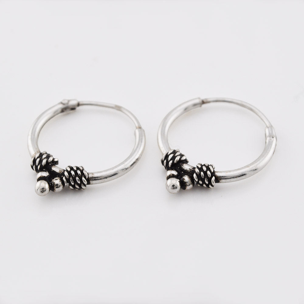 Silver bali earrings with triple dots and weave design on a white background
