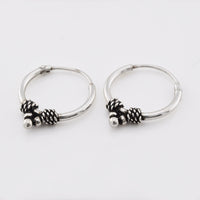 Silver bali earrings with triple dots and weave design on a white background