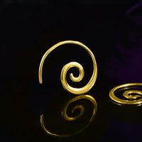gold spiral earrings on a black reflective background

