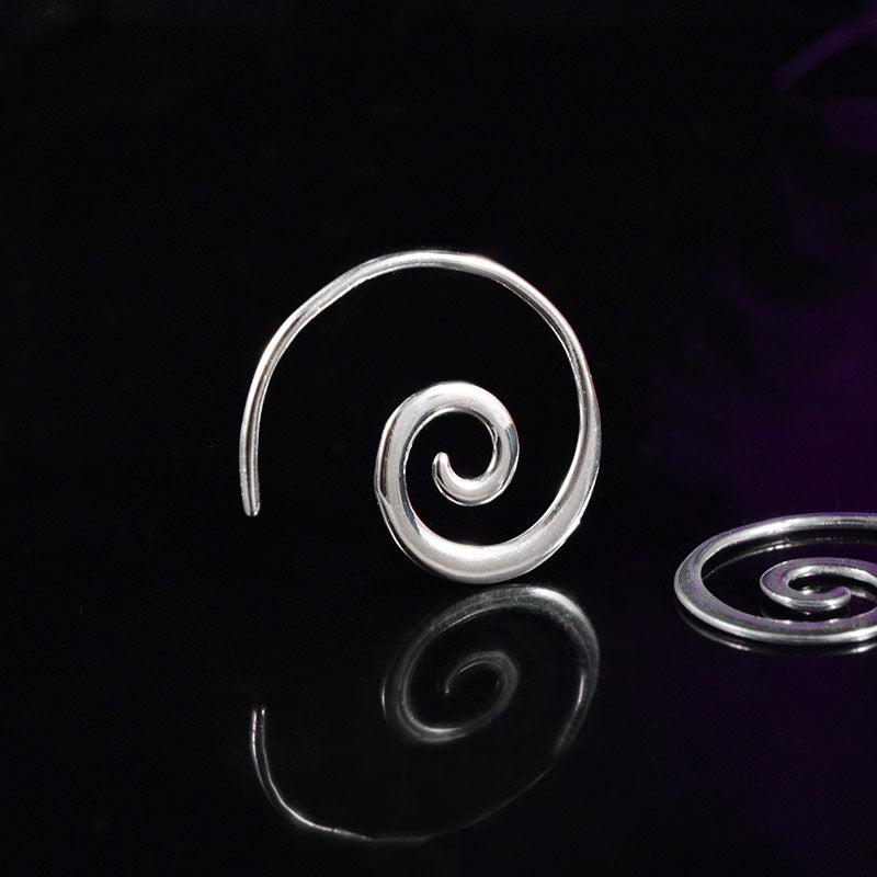 silver spiral earrings on a black reflective background