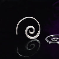 silver spiral earrings on a black reflective background