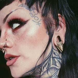 woman wearing shark tooth ear weights in her stretched ears