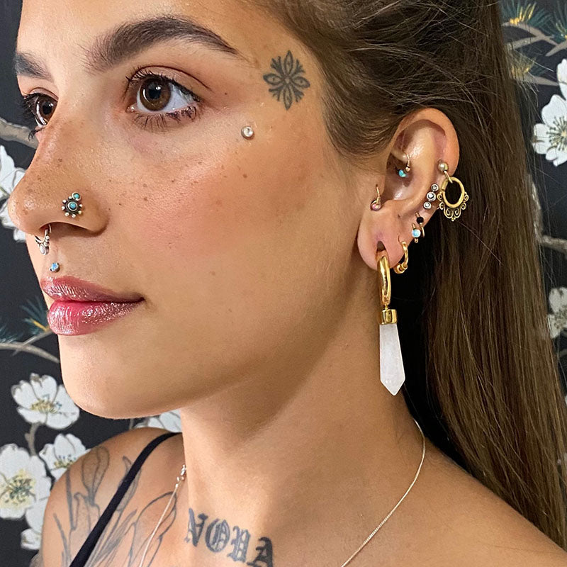 close up of an alternative woman with helix earrings, piercings and tattoos