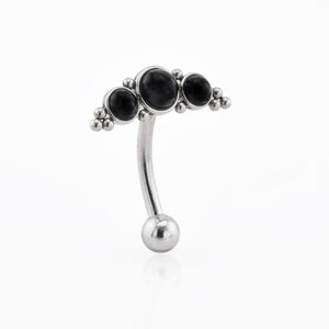 Silver belly button ring with black stones on a white background