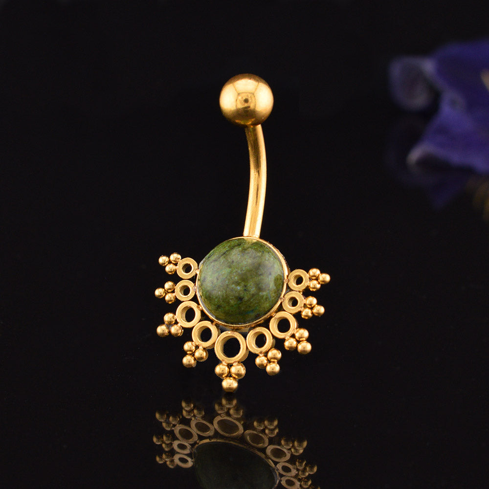 Gold-plated curved barbell belly button ring with a round green african jade stone centerpiece and ornate filigree details, shown on a reflective black background.