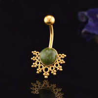 Gold-plated curved barbell belly button ring with a round green african jade stone centerpiece and ornate filigree details, shown on a reflective black background.