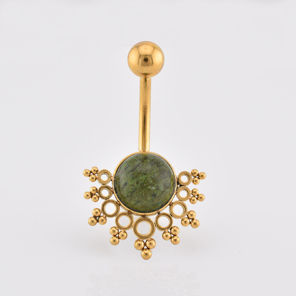 Tribal Navel Bar, Gold-plated navel jewelry featuring a round green afircan jade stone centerpiece surrounded by decorative gold filigree, on a plain light gray background.