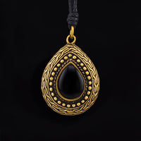 Gold Brass and Black Onyx tribal teardrop pendant on a black background