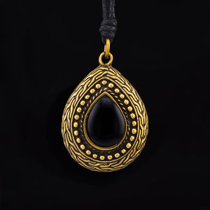 Gold Brass and Black Onyx tribal teardrop pendant on a black background