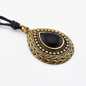 Gold brass pendant with black onyx stone on a white background