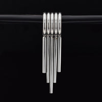 set of 5 clicker rings with drop spikes for wearing in stretched ears in surgical steel on a black background