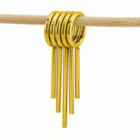 Stack of 5 gold coloured clicker rings with drop spikes for wearing in stretched ears   hanging from a light natural wood rod against a solid white background.