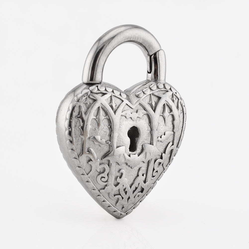 A heart-shaped silver steel padlock ear weight with intricate filigree cutouts of bats and architecture and a keyhole in the center, shown on a clean white background.