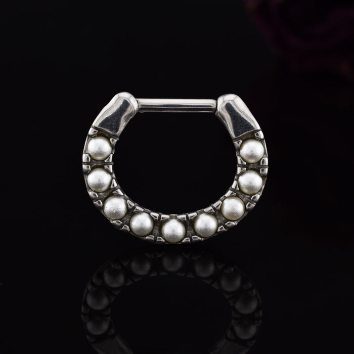Silver steel septum clicker ring with pearls on a black background