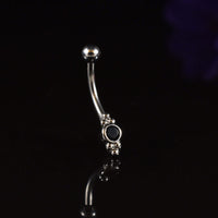 A curved barbell with triple beads and black stones shown on a reflective black background.