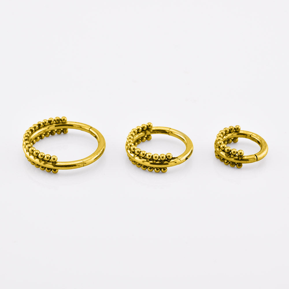 Three gold-colored beaded hoop earrings in different sizes, arranged horizontally on a clean white background.