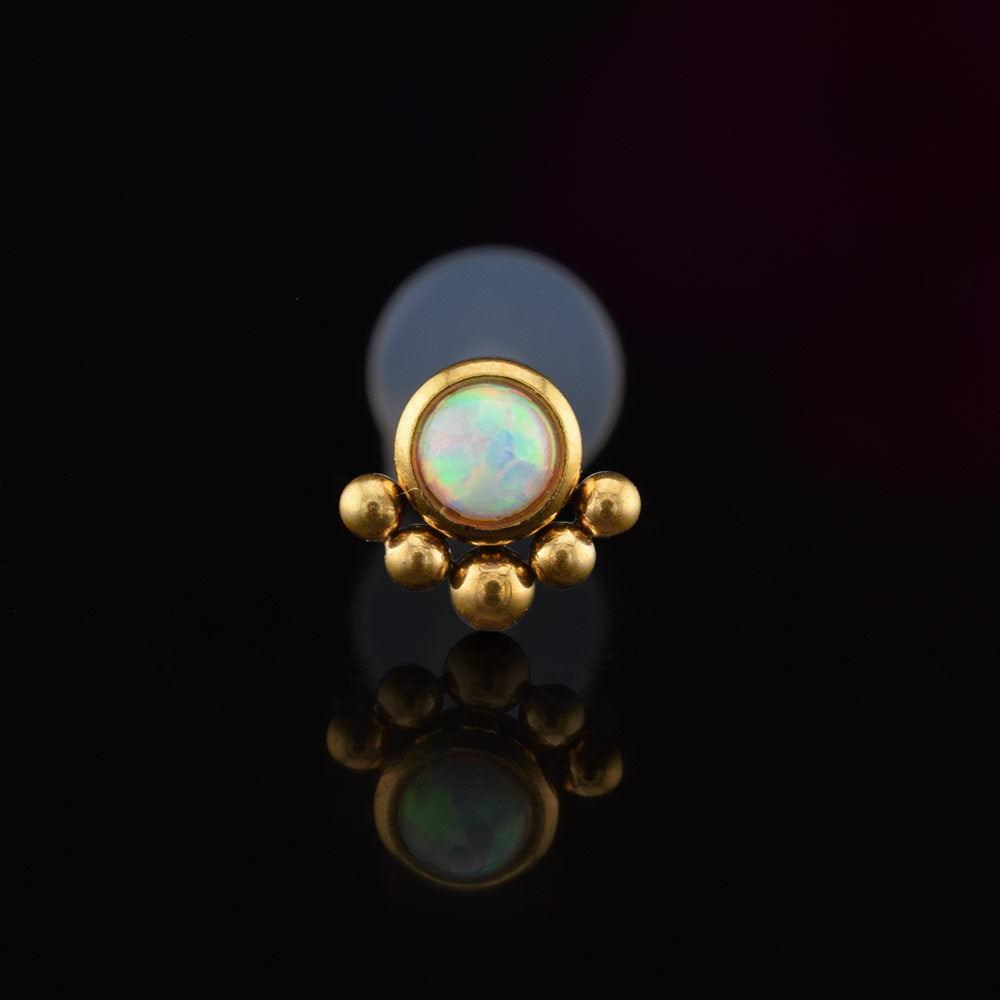 BioFlex PTFE labret with an opal stone and gold tribal beading on a black background