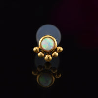 BioFlex PTFE labret with an opal stone and gold tribal beading on a black background