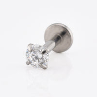 A single solitaire labret stud earring featuring a round brilliant-cut clear gemstone in a four-prong setting on a polished silver-tone metal post with a flat circular backing, shown on a clean white reflective surface.