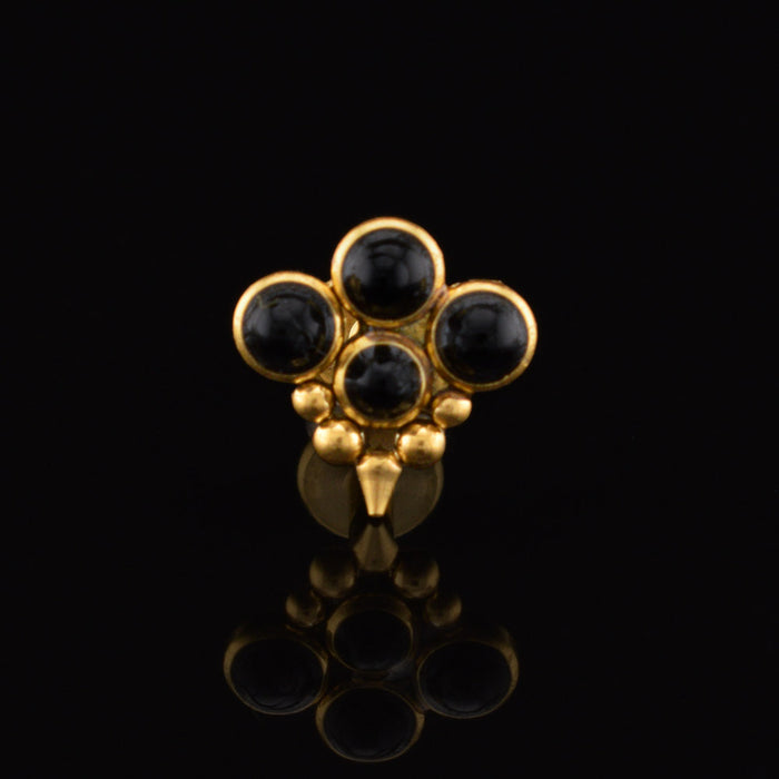 gold steel labret stud jewellerywith four black onyx stones, tribal beads and a drop spike on a black reflective background