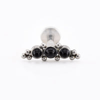 A silver-toned body jewelry piece, likely a labret or piercing stud, featuring three round black gemstones in a row with small metallic beads on each side, set against a plain white background.