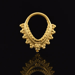 Gold septum ring with intricate indian design on a black background