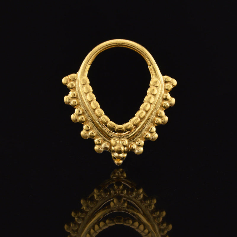 Gold septum ring with intricate indian design on a black background