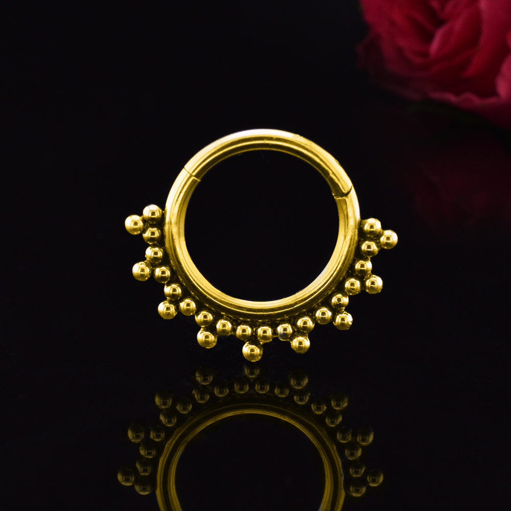 clicker ring or ear piercings  in gold steel with tribal beads decoration on black background