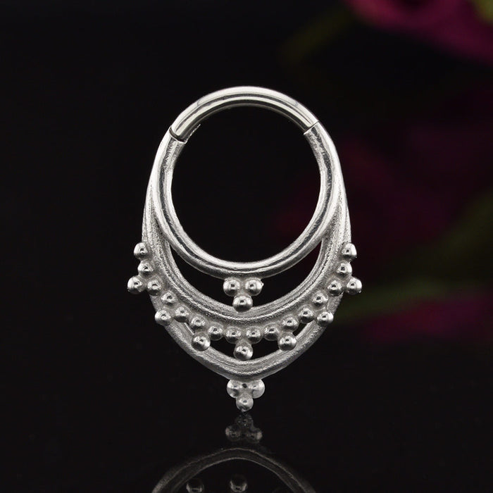 Tribal Clicker RIng aka hinged segment piercing ring in an Indian design on a black background