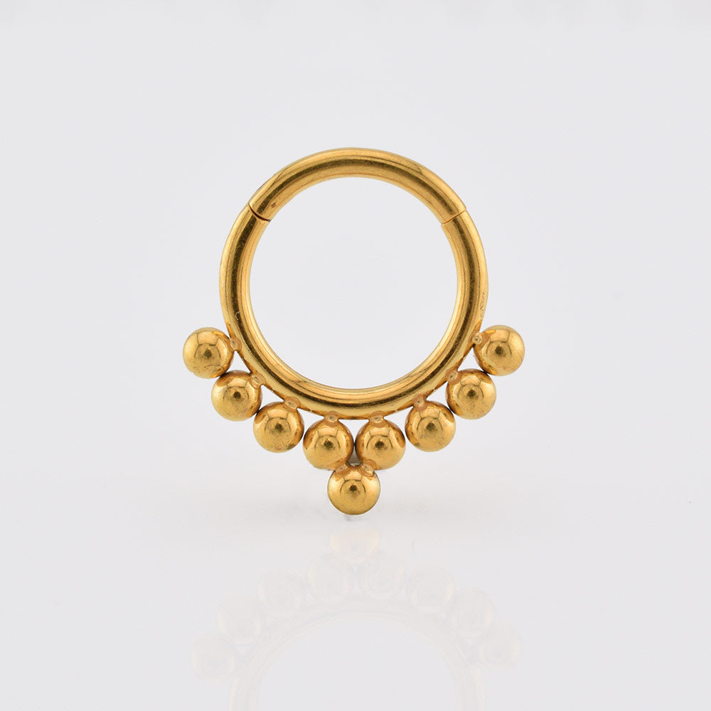 Gold septum ring with tribal beads on a white background