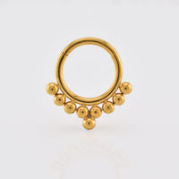 Gold septum ring with tribal beads on a white background