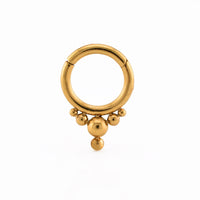 A gold  steel hoop hinged segment clicker ring with a fixed tribal beaded fringe, displayed on a white surface.