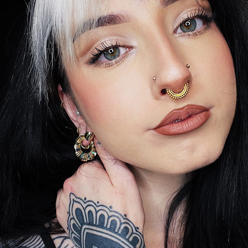 girl wearing ear weights and septum piercing with hand tattoo